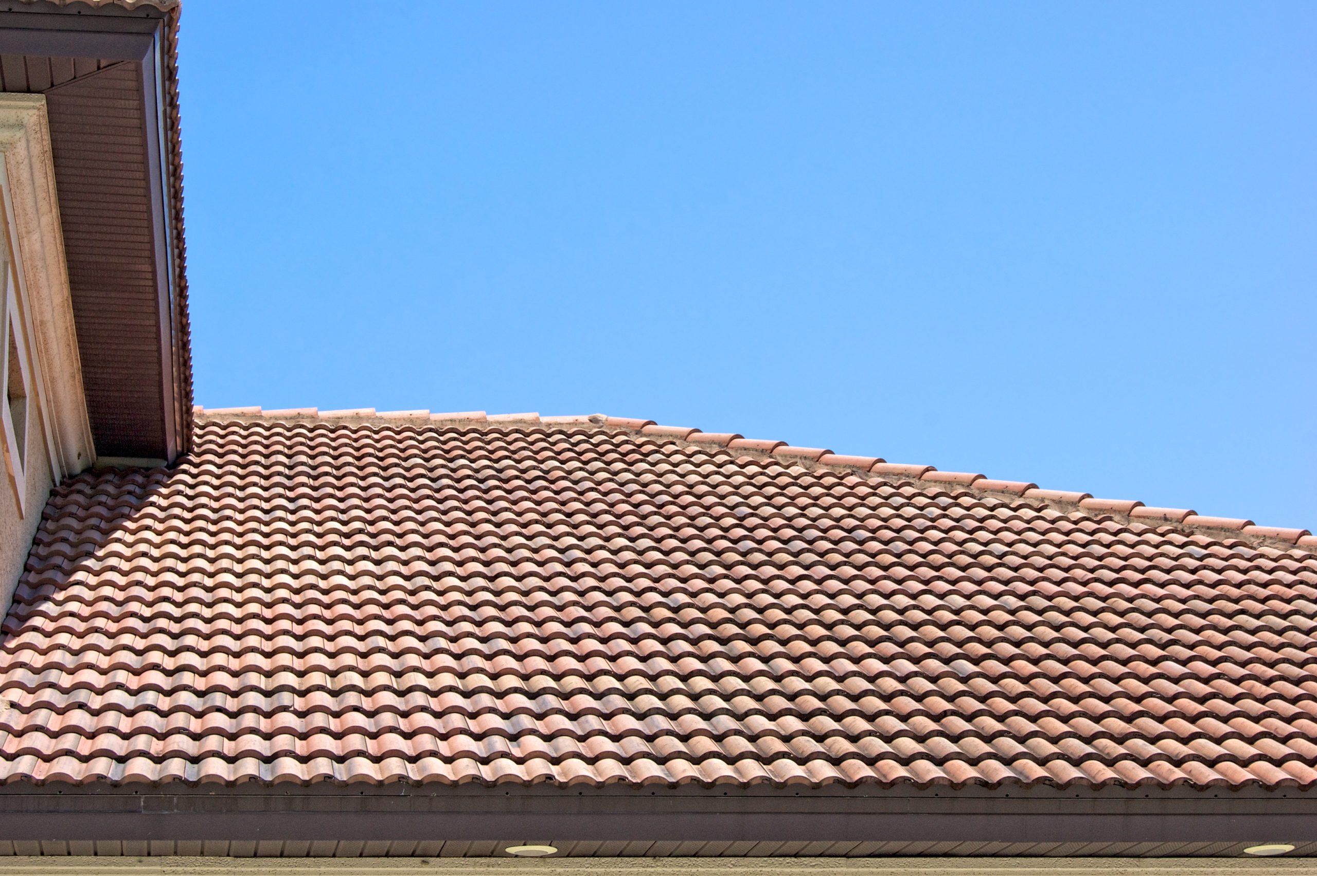 Peak of a clay tile roof with half round shingles against a blue sky in southern florida